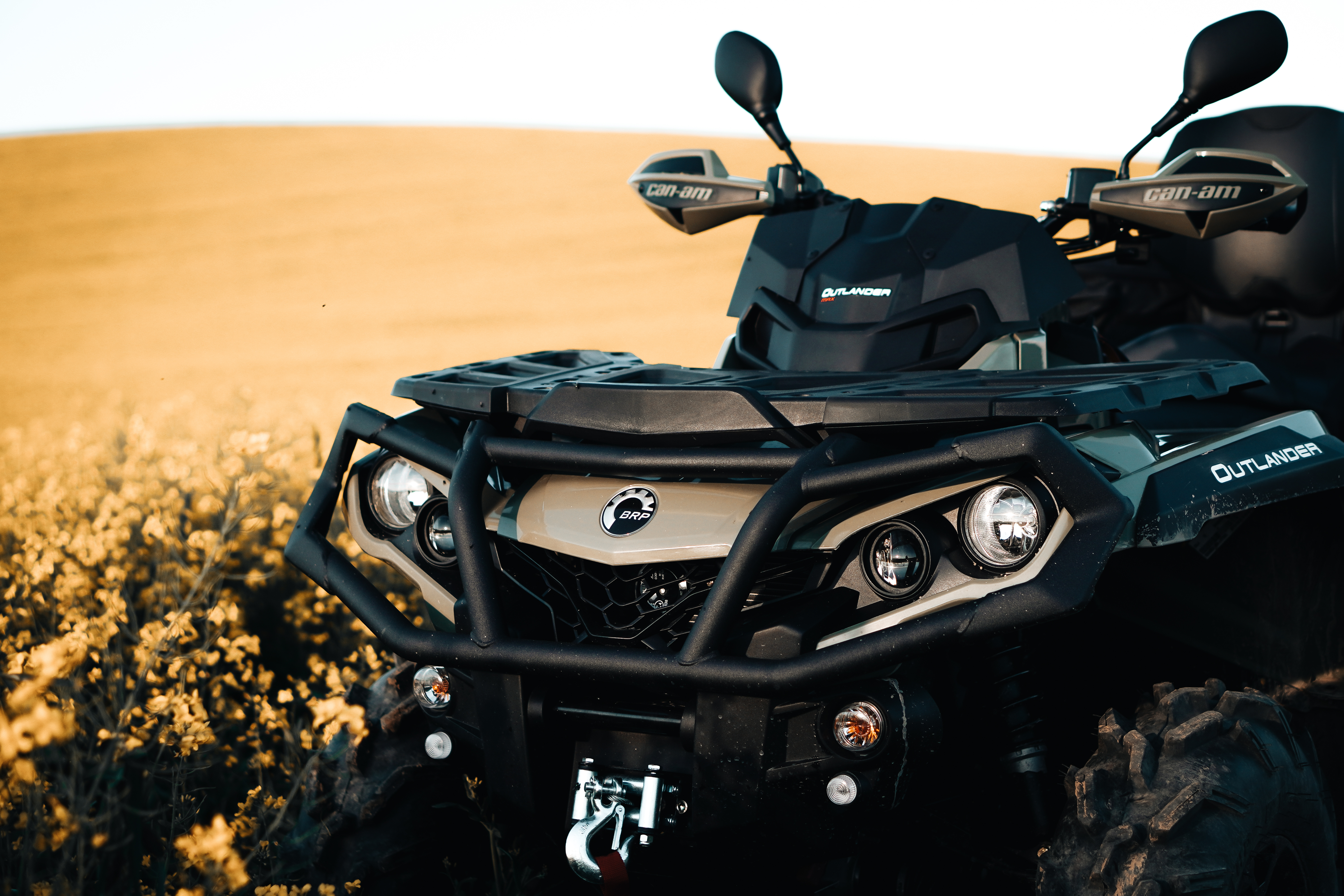 Detail close up of army green can-am outlander atv quad motorcycle bike’s front light. It look’s like very aggressive and strong off – road vehicle.